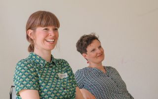 Sarah und Elisabeth hören Teilnehmer*innen zu